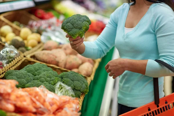 Woman with basket buying broccoli at grocery store — Stock Photo, Image