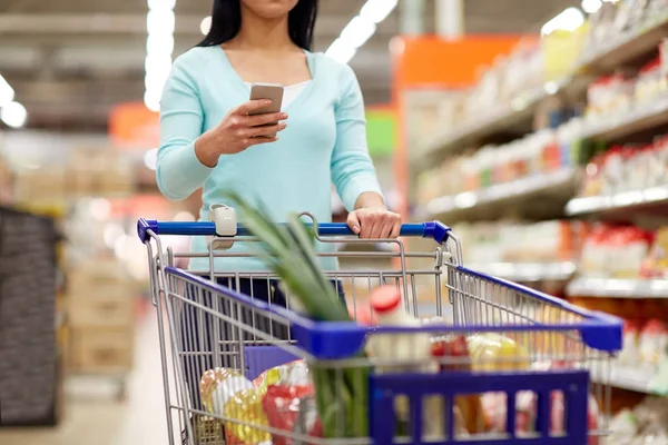 Vrouw met smartphone kopen van eten in supermarkt — Stockfoto