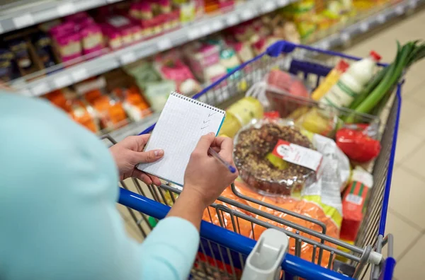 Frau mit Lebensmitteln im Einkaufswagen im Supermarkt — Stockfoto