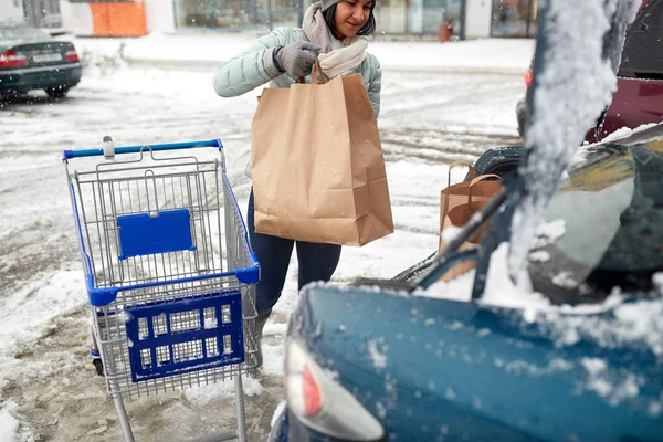 Mujer cargando comida desde el carrito de la compra al maletero Imágenes de stock libres de derechos