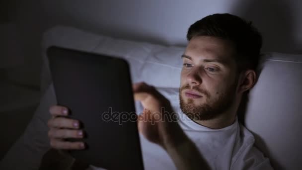 Jeune homme avec tablette PC dans le lit à la maison chambre — Video