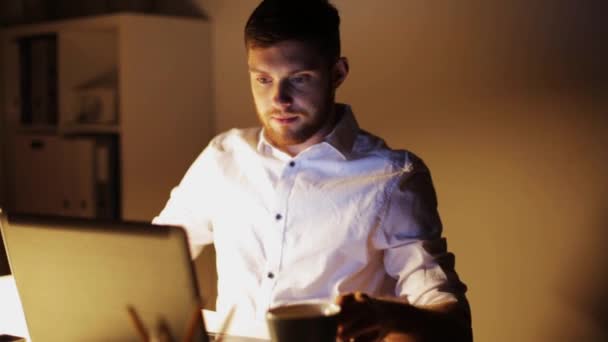 Hombre con portátil y café trabajando en la oficina de noche — Vídeo de stock