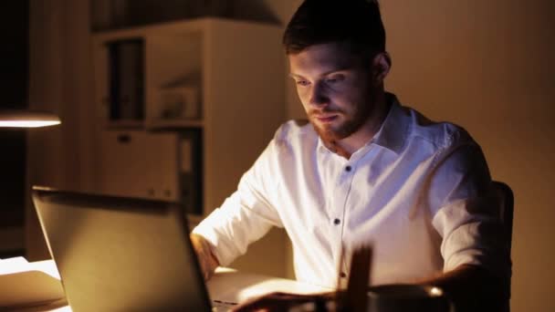 Homme avec le travail de finition d'ordinateur portable au bureau de nuit — Video