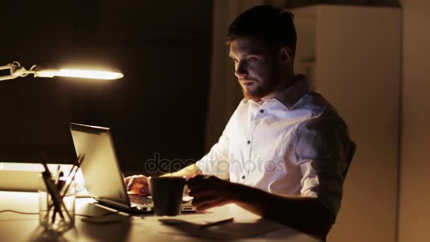 लैपटॉप और कॉफी के साथ आदमी रात कार्यालय में काम कर रहा है — स्टॉक वीडियो