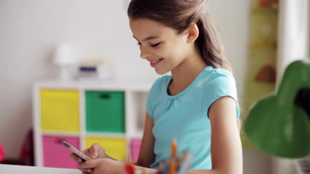 Chica sonriente mensajes de texto en el teléfono inteligente en casa — Vídeos de Stock