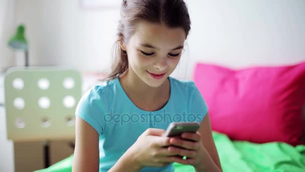 Χαμογελαστό κορίτσι γραπτών μηνυμάτων στο smartphone στο σπίτι — Αρχείο Βίντεο