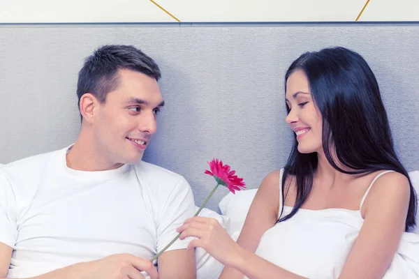 Lachende paar in bed met bloem — Stockfoto