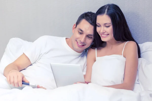 Lachende paar in bed met tablet pc-computers — Stockfoto