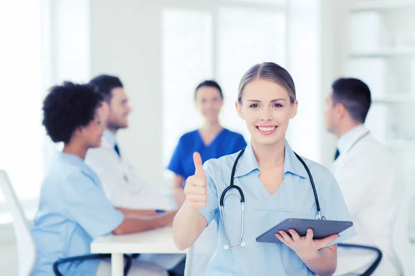 Zufriedener Arzt mit Tablet-PC über Team in Klinik — Stockfoto