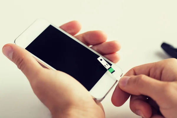 Close-up de homem com smartphone fazendo teste de sangue — Fotografia de Stock