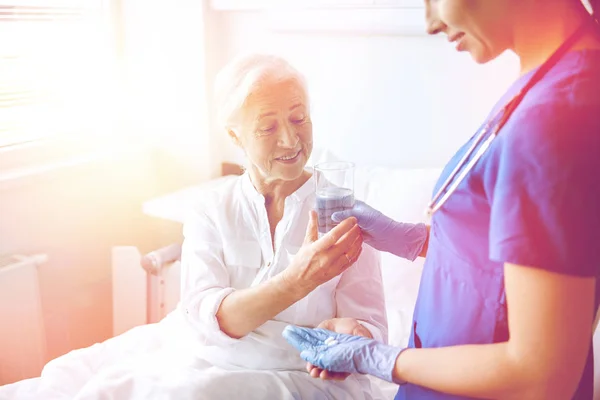 Enfermera que da medicina a una mujer mayor en el hospital —  Fotos de Stock