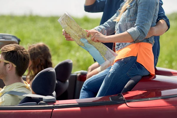 Amigos felizes com mapa dirigindo em carro conversível — Fotografia de Stock