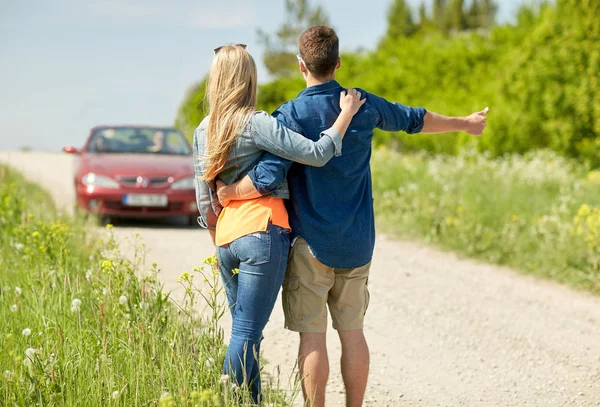 Couple hitchhiking and stopping car on countryside — Stock Photo, Image