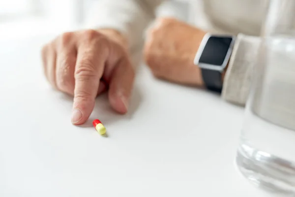 Close up de mão de homem velho com pílula e relógio inteligente — Fotografia de Stock