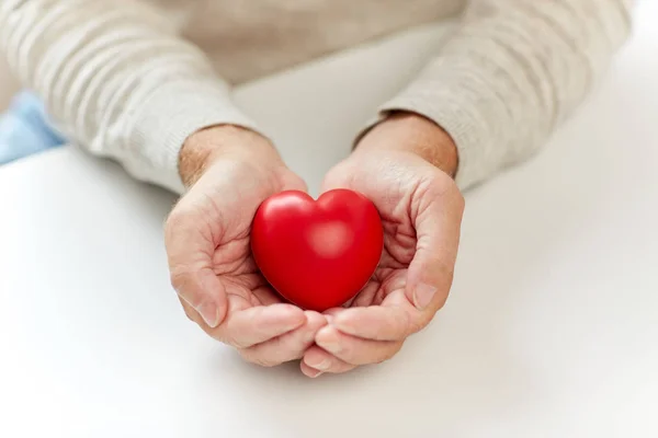 Крупным планом пожилой человек с красным сердцем в руках — стоковое фото