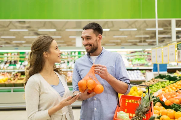 Lyckliga paret att köpa apelsiner på mataffären — Stockfoto