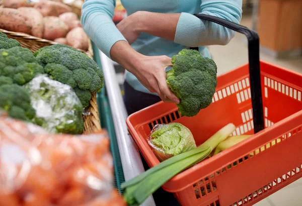 Mujer con cesta comprando brócoli en la tienda de comestibles — Foto de Stock