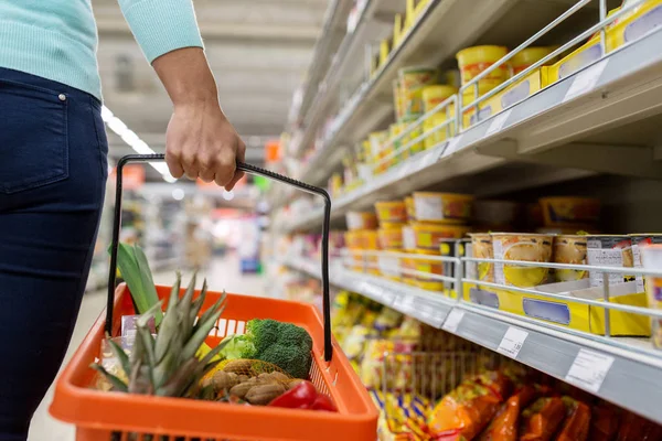 Vrouw met levensmiddelen mand bij de kruidenier of supermarkt — Stockfoto