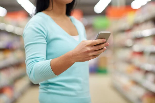 Kvinna med smartphone på butik eller stormarknad — Stockfoto