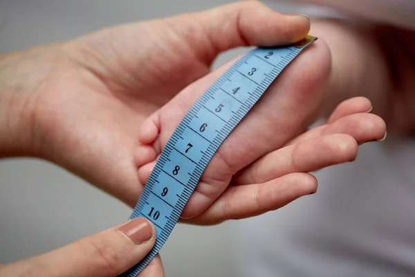 Close up of hands with tape measuring baby foot — Stock Photo, Image