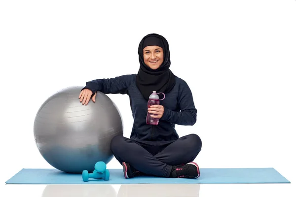 Mulher muçulmana em hijab com bola de fitness e garrafa — Fotografia de Stock