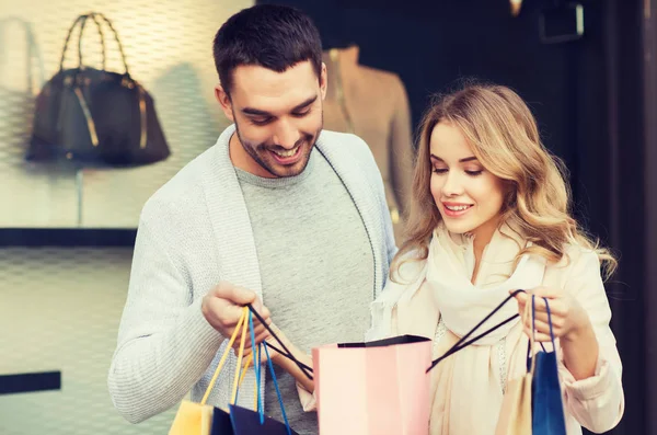 Gelukkige paar met shopping tassen bij etalage — Stockfoto
