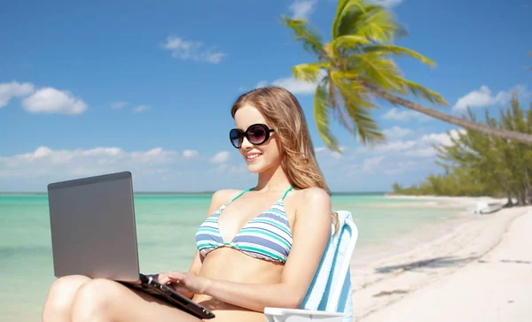 Frau mit Laptop sonnt sich in Lounge am Strand — Stockfoto