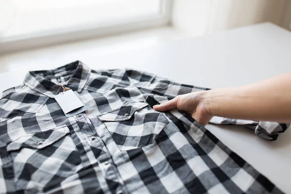 Close up of hand and shirt with price tag — Stock Photo, Image