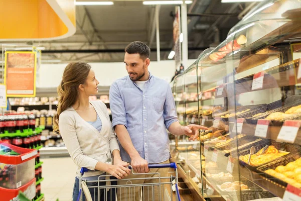 Gelukkige paar met winkelwagentje in supermarkt — Stockfoto