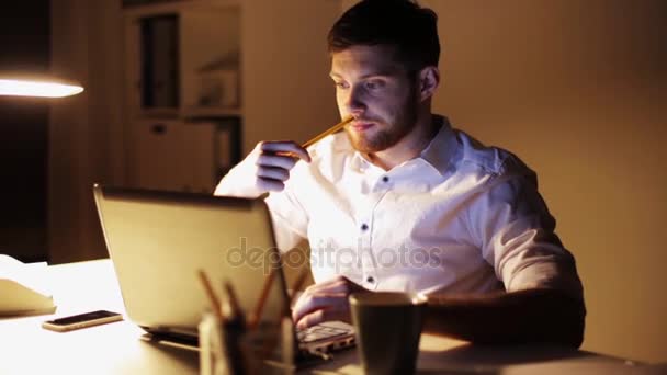 Mann mit Laptop und Papieren arbeitet nachts im Büro — Stockvideo