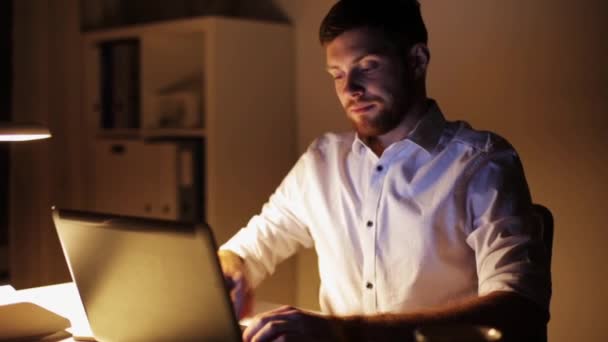 Человек с ноутбуком и смартфоном в ночном офисе — стоковое видео
