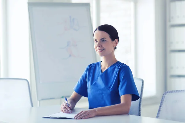 Feliz doctora o enfermera escribiendo al portapapeles — Foto de Stock