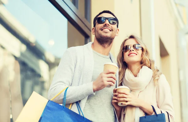 Casal feliz com sacos de compras e café na cidade — Fotografia de Stock