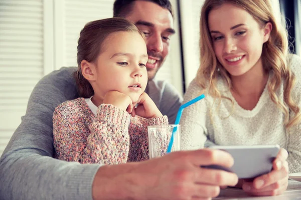 Lycklig familj med smartphone på restaurang — Stockfoto