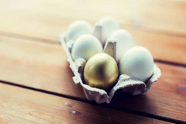 Närbild av vitt och guld ägg i ägg låda — Stockfoto