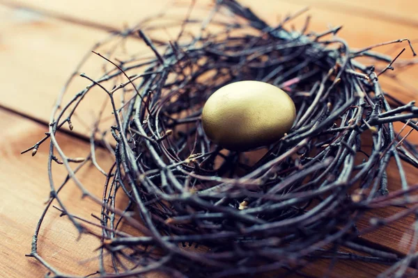Närbild av gyllene påsk ägg i boet på trä — Stockfoto