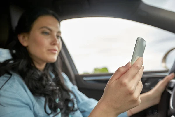 Жінка за кермом автомобіля з смартфоном — стокове фото