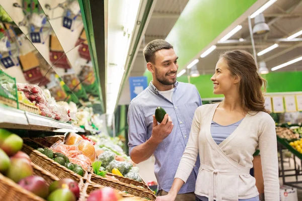 Happy couple buying avocado at grocery store — Stock Photo, Image