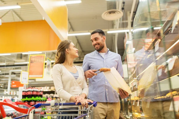 Casal feliz com carrinho de compras na mercearia — Fotografia de Stock