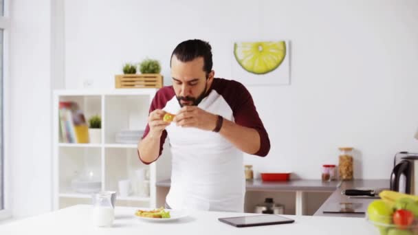 Ο άνθρωπος με το tablet pc που τρώει πρωινό στο σπίτι — Αρχείο Βίντεο