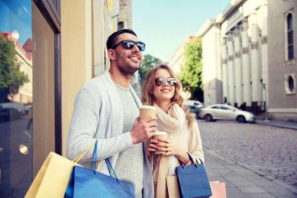 Casal feliz com sacos de compras e café na cidade — Fotografia de Stock