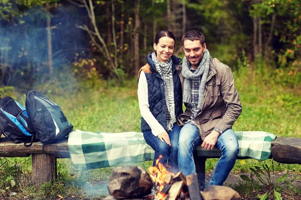 Happy couple sitting on bench near camp fire — Stock Photo, Image