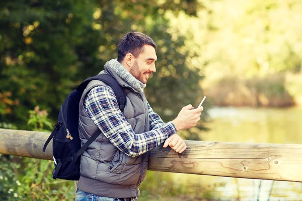 Glücklicher Mann mit Rucksack und Smartphone im Freien — Stockfoto