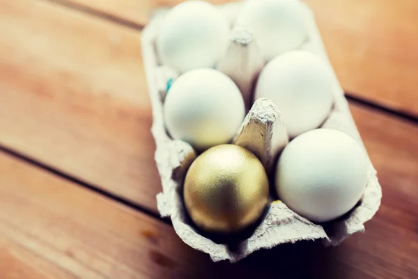 Närbild av vitt och guld ägg i ägg låda — Stockfoto