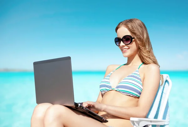 Woman with laptop sunbathing in lounge on beach — Stock Photo, Image