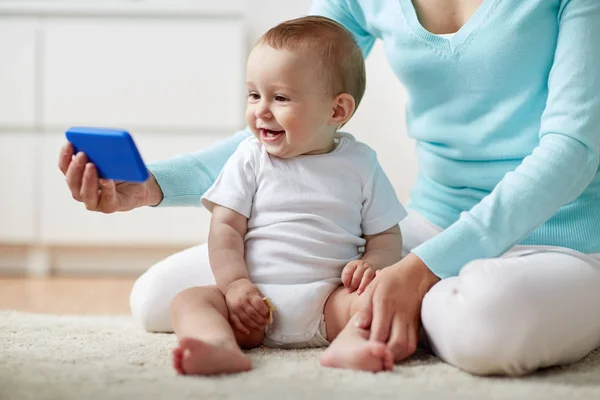 Lycklig mamma visar smartphone för bebisen hemma — Stockfoto