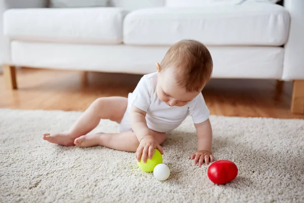 Bebê feliz brincando com bolas no chão em casa — Fotografia de Stock