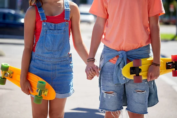 Primer plano de pareja joven con patinetas en la ciudad — Foto de Stock