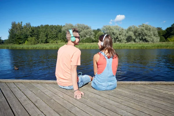 Tiener koppel met koptelefoon op rivier ligplaats — Stockfoto