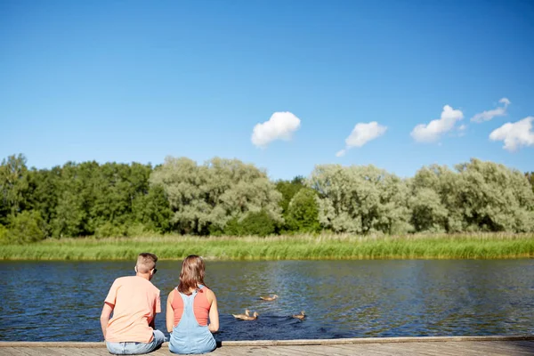 Coppia sull'ormeggio del fiume guardando anatre nuoto — Foto Stock